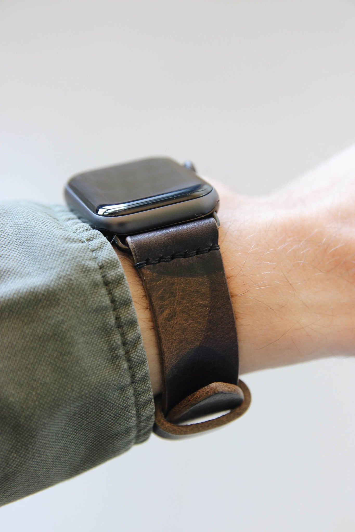 Seitenansicht einer Apple Watch am Handgelenk mit einem Lederband in Camouflage.