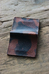 Rückseite eines Leder Kartenetuis in Camouflage auf einer Holzplatte.