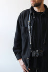 Leder Kameragurt in Schwarz um den Hals getragen in Nahaufnahme.
