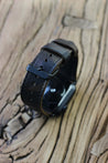 Apple Watch mit einem Apple Watch Lederarmband in Camouflage auf einer Holzplatte.
