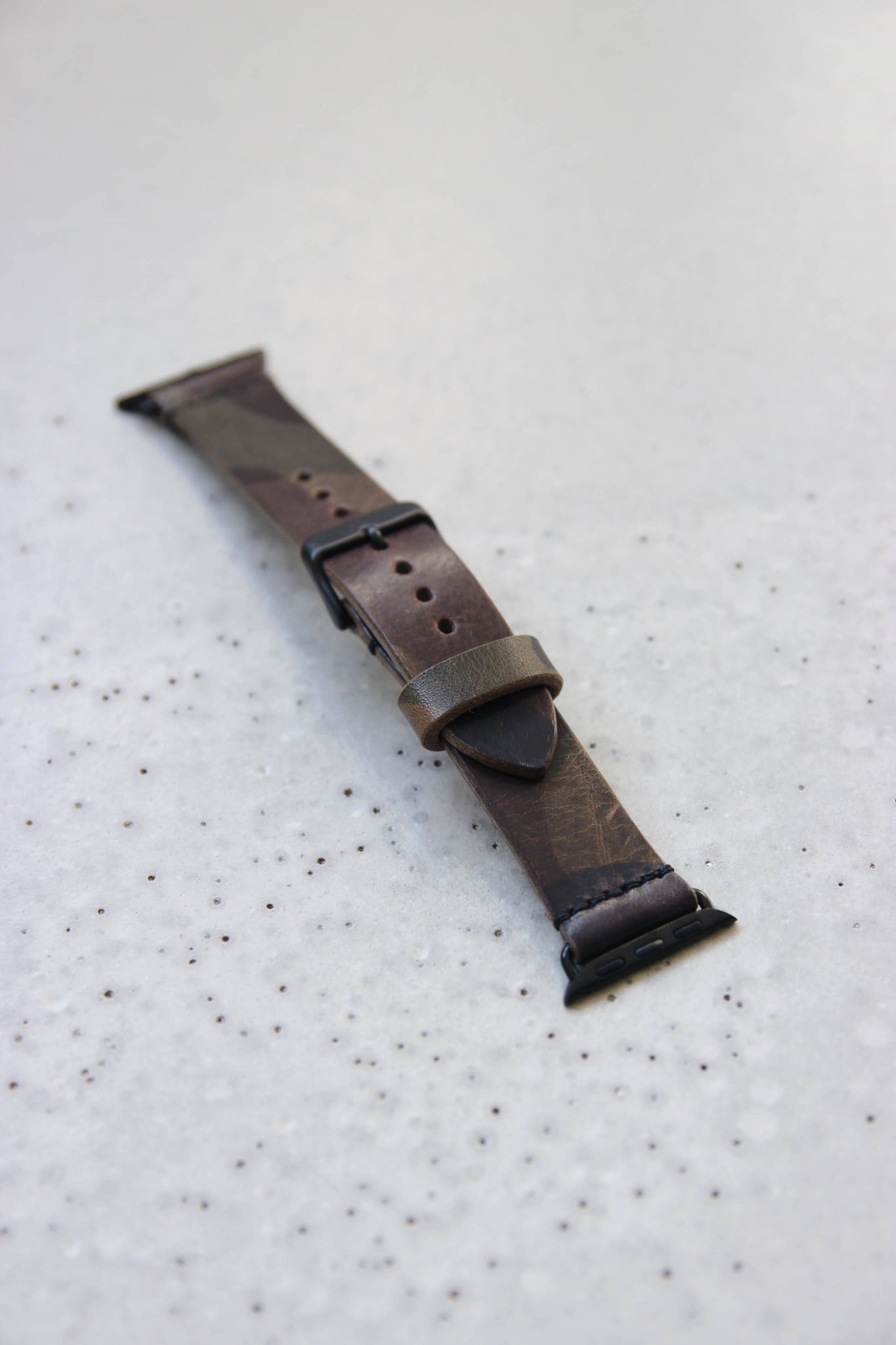 Apple Watch Lederband in Camouflage auf einem Betonboden liegend.
