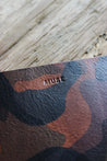 Nahaufnahme des Logos einer Leder MacBook Hülle in Camouflage.