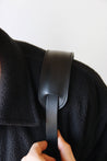 Schulterpad von einem Leder Kameragurt in Schwarz in Nahaufnahme und über der Schulter getragen.